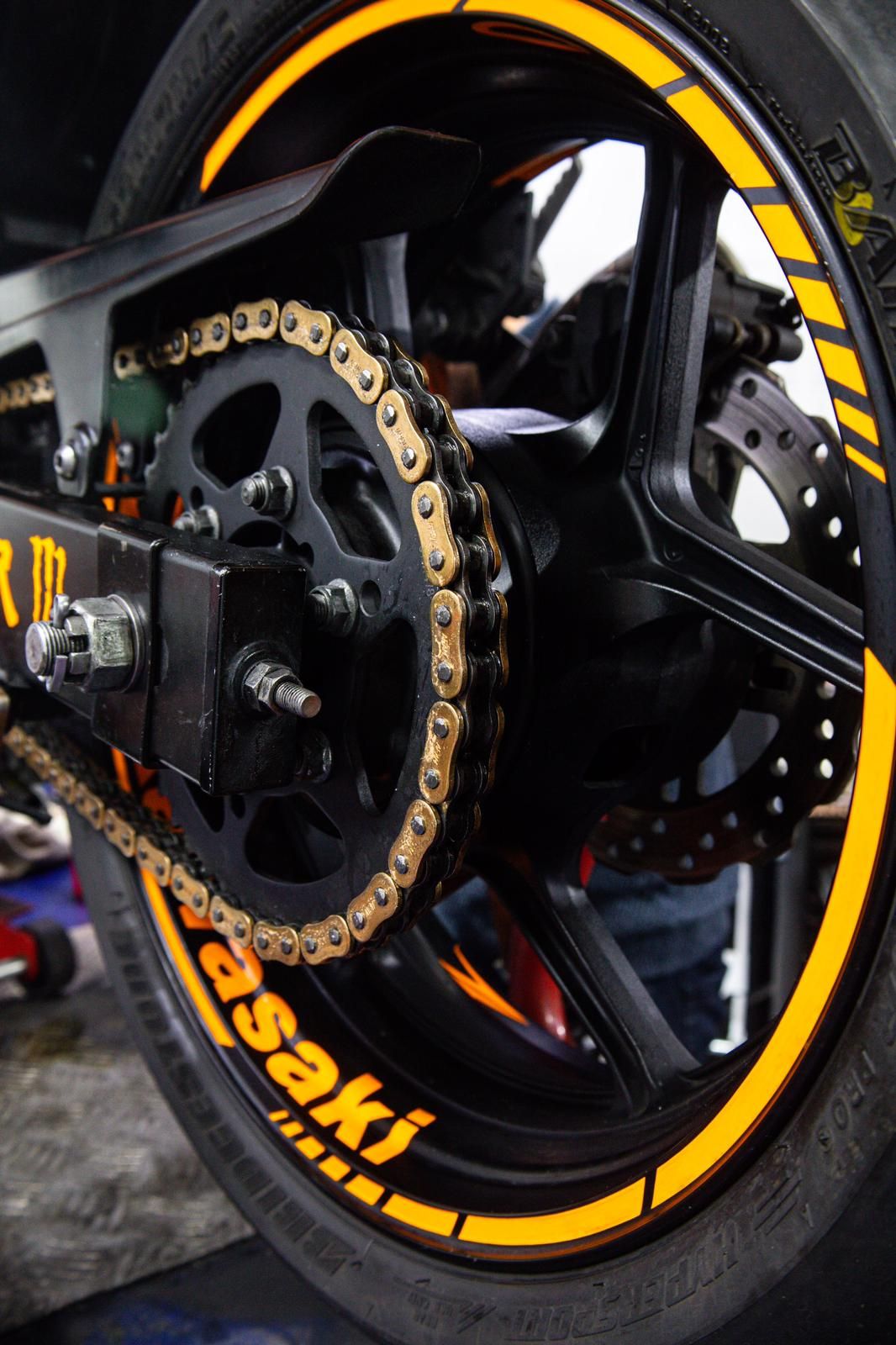 La imagen muestra una rueda de motocicleta con un diseño de neón amarillo y negro, que se encuent...